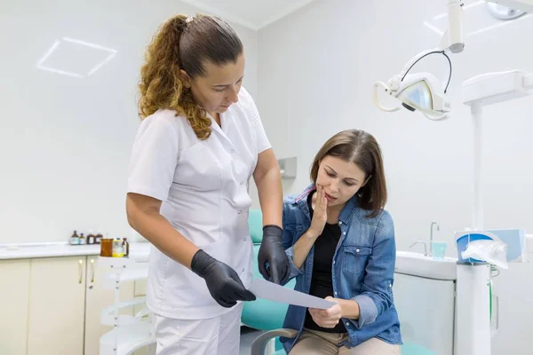 Tandläkaren visar en patient hennes tänder röntgen. Hälsovård, sjukvård och tandvård koncept — Stockfoto