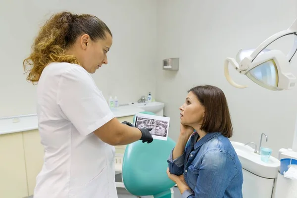Tandläkaren visar en patient hennes tänder röntgen. Hälsovård, sjukvård och tandvård koncept — Stockfoto