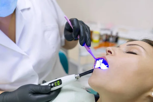 Medicine, dentistry and healthcare concept. Close-up partial view of dentist using dental curing UV lamp on teeth of patient — Stock Photo, Image