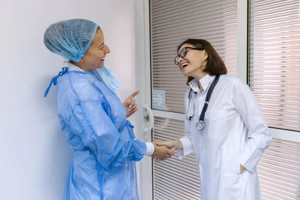 Duas mulheres médico e cirurgião conversando no hospital no fundo da porta — Fotografia de Stock