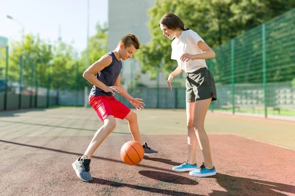 Streetball jogo de basquete com dois jogadores, menina e menino adolescentes, manhã no campo de basquete — Fotografia de Stock