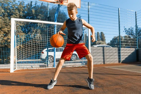 Caucásico adolescente niño calle baloncesto jugador con pelota en al aire libre ciudad baloncesto cancha — Foto de Stock