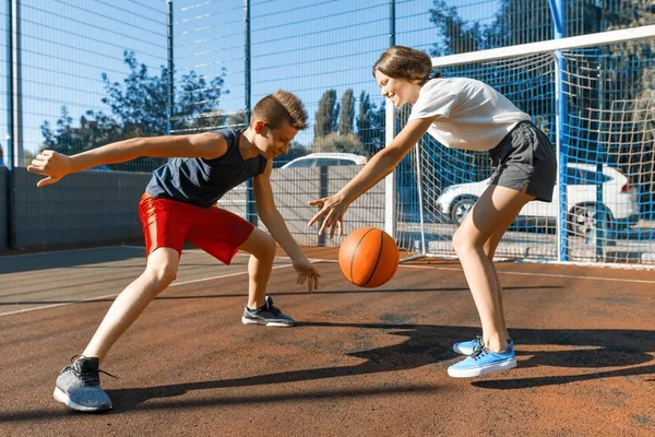 Streetball gioco di basket con due giocatori, adolescente ragazza e ragazzo con la palla, campo da basket all'aperto della città . — Foto Stock