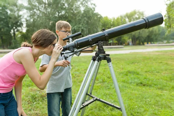 Niños adolescentes con telescopio miran al cielo en la naturaleza —  Fotos de Stock