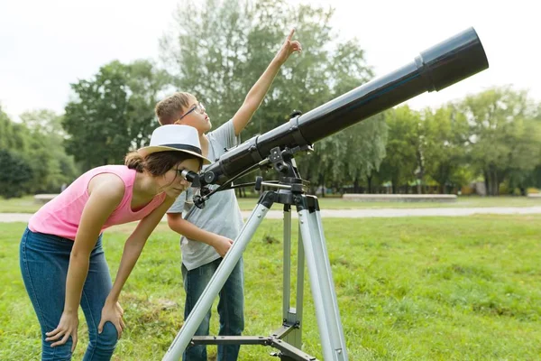 Niños adolescentes en el parque mirando a través de un telescopio — Foto de Stock