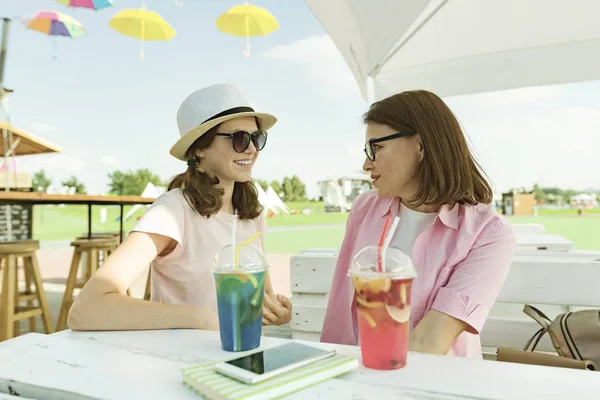 Communication of parent and teenager. Mother and daughter teenager talking sitting in summer street cafe