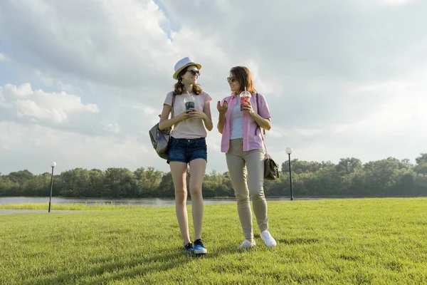 Comunicazione di genitori e adolescenti. La madre sta parlando con sua figlia adolescente per 14 anni, passeggiando per il parco nella soleggiata giornata estiva. Natura, cielo in nuvole sfondo, ora d'oro — Foto Stock