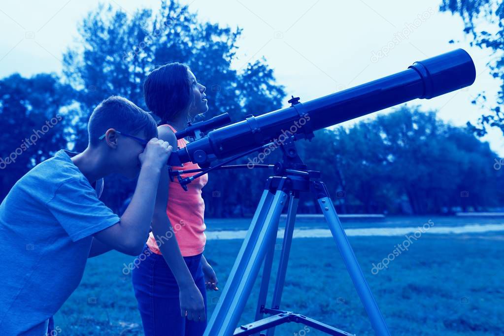 Teens with a telescope in the evening. Children looking with interest in the sky