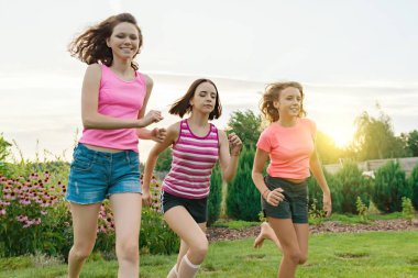 Yaz günbatımı zemin karşı yeşil çim üzerinde çalışan üç genç spor kızlar Genç