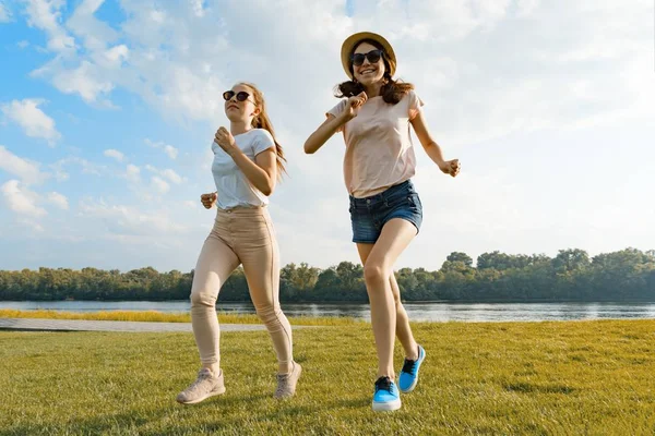 Młode dziewczyny są uruchomione. Nastolatki zabawy na zielony trawnik w parku, korzystających słoneczny letni dzień, złotej godziny — Zdjęcie stockowe