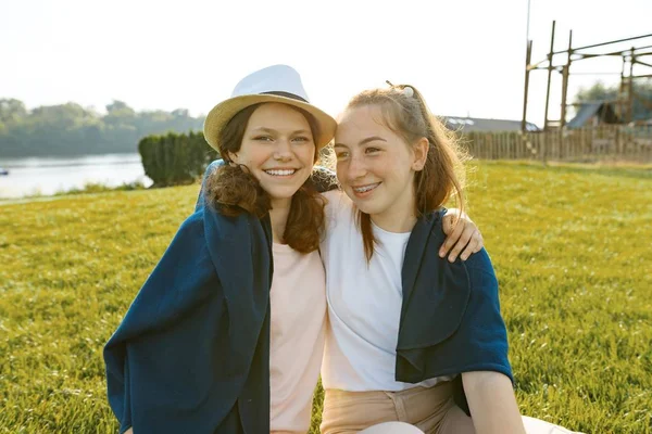 Dois jovens amigos sorridentes menina sentar abraçando na grama verde no verão ensolarado parque — Fotografia de Stock