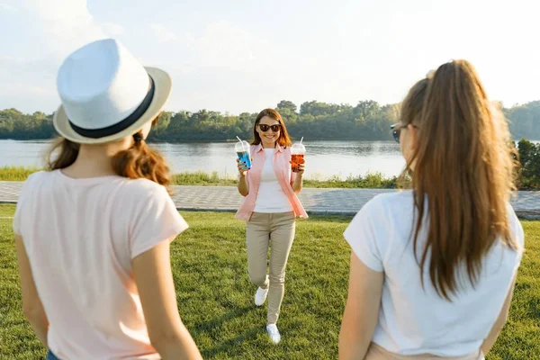 Счастливая мать отдыхает на природе со своими дочерьми-подростками 14 и 16 лет. Общение родителей и подростков, Женщина с летними напитками — стоковое фото