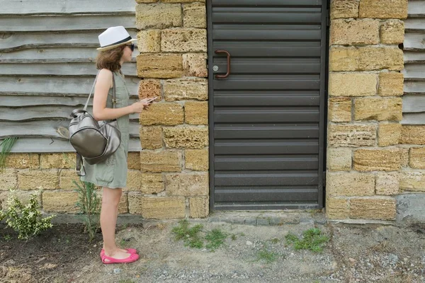 All'aperto ragazza chiama il citofono, in piedi vicino alla porta d'ingresso — Foto Stock