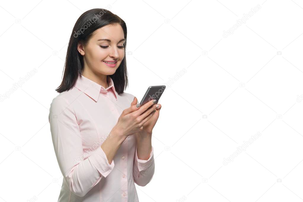 Young businesswoman in pink shirt using mobile phone on white isolated background. Woman writing or reading text message on modern smartphone, copy space