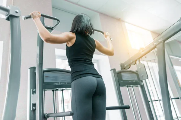 Giovane donna che fa esercizi per la schiena sulla macchina fitness in palestra, vista dalla schiena. Fitness, sport, allenamento, concetto di persone . — Foto Stock