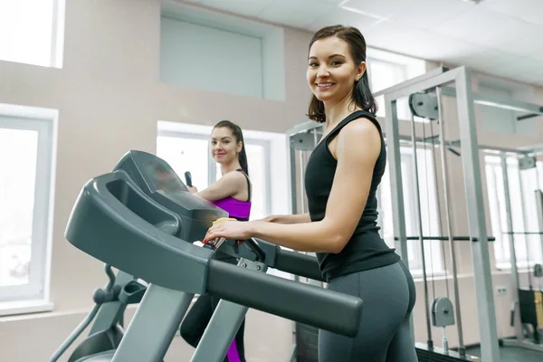 Két fiatal fitness egészséges nők futópad sport modern edzőteremben. Fitness, sport, képzés, emberek koncepció. — Stock Fotó