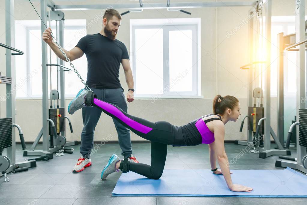 Kinesis technology, kinesitherapy, healthy lifestyle. Young woman doing rehabilitation exercises with personal instructor using kinesi machine