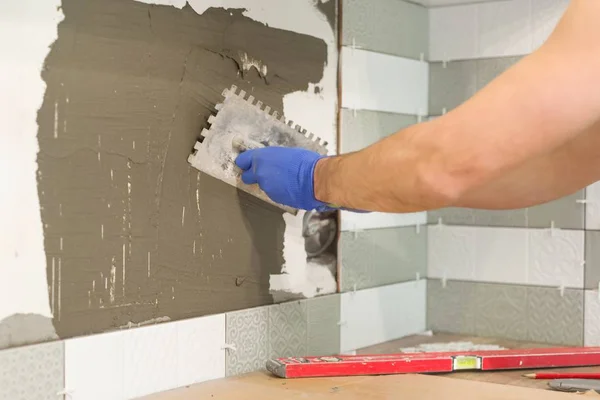 Reparatie en bouw van de keuken, handen van tegelzetter het installeren van keramische tegels op de muur, gebruik maken van professionele gereedschappen, echte leggen proces — Stockfoto