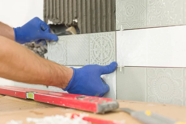 Closeup of tiler hand laying ceramic tile on wall in kitchen, renovation, repair, construction — Stock Photo, Image