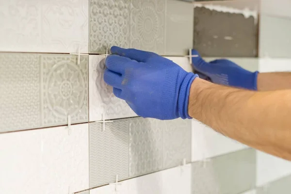 Instalando telhas cerâmicas na parede na cozinha. Colocação de espaçadores de azulejos com as mãos, renovação, reparação, construção . — Fotografia de Stock