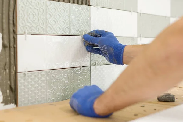 Installazione di piastrelle di ceramica sulla parete in cucina. Posizionamento distanziali piastrelle con le mani, ristrutturazione, riparazione, costruzione . — Foto Stock