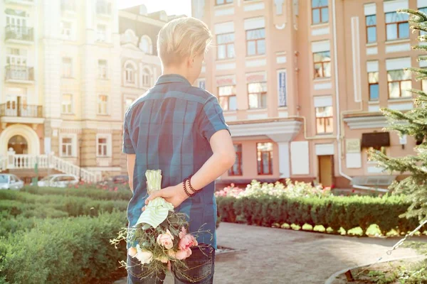 Tinédzser fiú gazdaság csokor virágot háta mögött. Meglepetés, ajándék, jelen — Stock Fotó