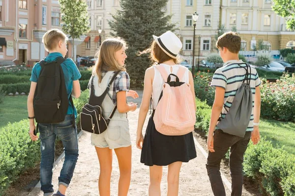 Jonge mensen vrienden wandelen in de stad, een groep tieners praten lachend plezier in de stad, uitzicht vanaf de achterkant. Vriendschap en mensen concept — Stockfoto