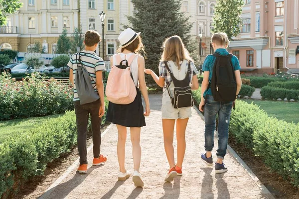 Jonge mensen vrienden wandelen in de stad, een groep tieners praten lachend plezier in de stad, uitzicht vanaf de achterkant. Vriendschap en mensen concept — Stockfoto