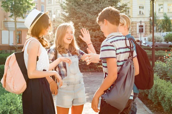 Зустрічаючись з усміхненими друзями-підлітками в місті, щаслива молодь вітає один одного, обіймаючи п'ятьох. Концепція дружби і людей — стокове фото