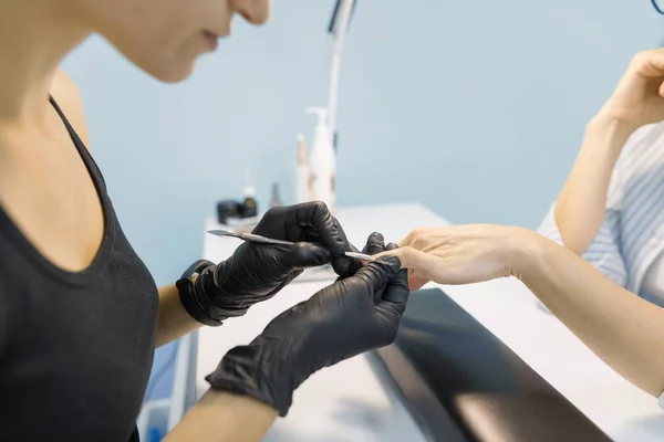 Nahaufnahme Prozess der professionellen Maniküre. Maniküre Frau Hände in schwarzen Handschuhen Herstellung Maniküre mit professionellen Werkzeugen. Nagel- und Handpflege im Schönheitssalon — Stockfoto