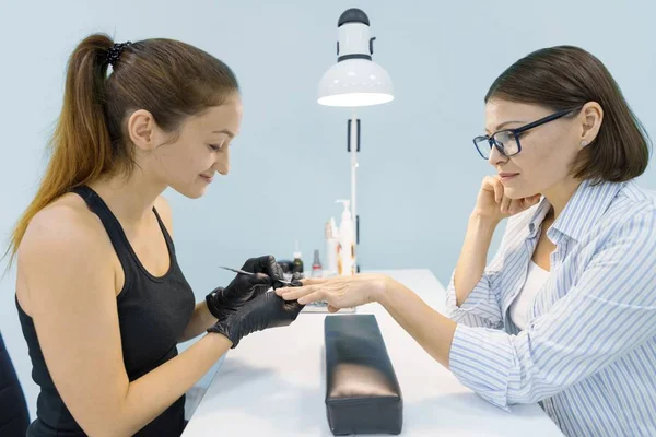 Young lachende vrouw schoonheidsspecialiste in nagel schoonheidssalon doen manicure met professionele gereedschappen, verzorging nagel en hand — Stockfoto