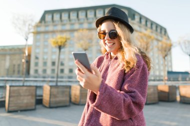 Cep telefonu ile şapka ve Gözlük Genç kız hipster, altın saat.