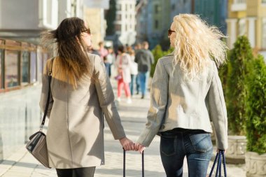 İki genç kadın bir şehir Sokağı boyunca yürüyüş, güneşli sonbahar günü, altın saat, arka görünüm