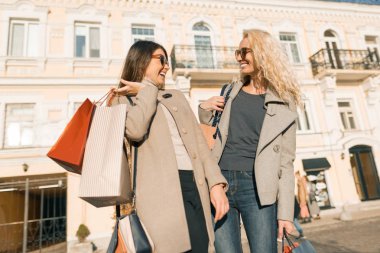 Alışveriş çantaları, güneşli sonbahar günü, altın saat ile bir şehir sokakta iki genç gülümseyen kadın
