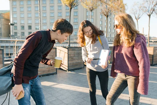 Middelbare scholieren praten buiten. Meisje tiener laten zien op een schone witte vel in notebook en jongen te kijken naar notebook, het gouden uur — Stockfoto