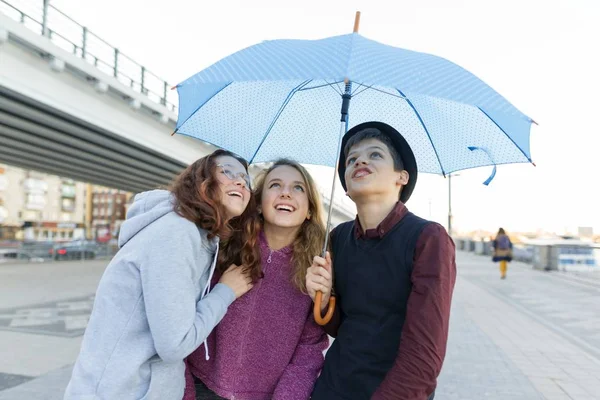 Gruppe befreundeter Teenager, die sich in der Stadt amüsieren, lachende Kinder mit Regenschirm. urbaner Lebensstil für Teenager. — Stockfoto
