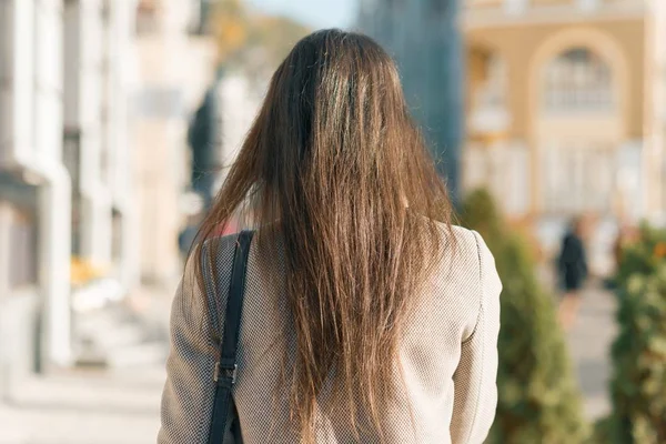 Pohled zezadu mladé brunetní ženy, procházky po městské ulici, podzimní slunný den — Stock fotografie