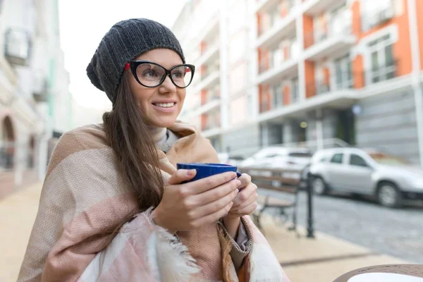 Retrato de inverno de outono de jovem mulher sorridente em chapéu, com xícara de bebida quente. Cidade rua fundo — Fotografia de Stock