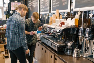 Kahve evi, küçük işletme, erkek barista kahve makinesi yakınındaki. Deneyimli barista koçluk profesyonel kahve makinesi kahve demlemek için genç adam öğretim