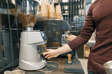Espresso kahve makinesi üzerinde hazırlanması, kahve çekirdekleri taşlama genç barista erkek