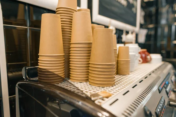 Café de papel kraft marrón tazas de primer plano en la máquina de café en el interior de la cafetería —  Fotos de Stock