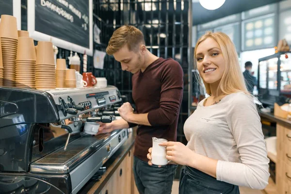 Мужчина и женщина-бариста, делающие кофе, пара молодых людей, работающих в кафе — стоковое фото