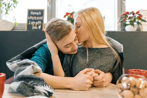 Besos abrazando joven pareja sentado en la cafetería juntos bajo una manta caliente —  Fotos de Stock