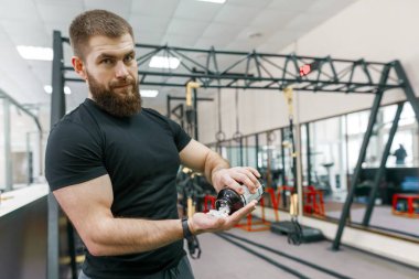 Spor ve fitness gösterilen sportif kaslı adam takviyeleri, kapsül, hap, spor salonu arka plan. Sağlıklı yaşam tarzı, tıp, beslenme takviyeleri ve insanlar kavramı