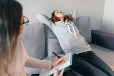 Genç kadın profesyonel psikoterapist ofisinde genç kız ile konuşurken. Ergenlik döneminde çocuk ruh sağlığı