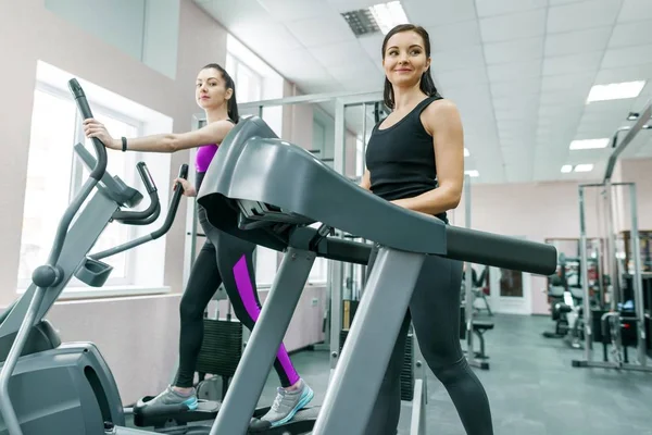 Két fiatal fitness egészséges nők futópad a sport modern edzőteremben. Fitness, sport, képzés, emberek koncepció — Stock Fotó