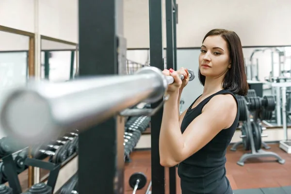 Giovane donna atletica che esercita sulle macchine in palestra sportiva moderna. Fitness, sport, allenamento, persone, concetto di stile di vita sano . — Foto Stock