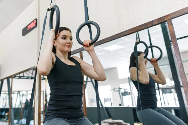 Young athletic woman exercising on the machines in modern sport gym. Fitness, sport, training, people, healthy lifestyle concept. — Stock Photo, Image