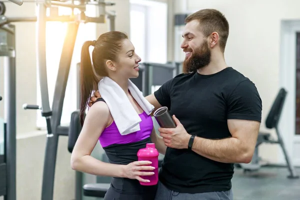 Joven pareja de fitness sonriente hablando en el gimnasio. Deporte, entrenamiento, familia y estilo de vida saludable —  Fotos de Stock