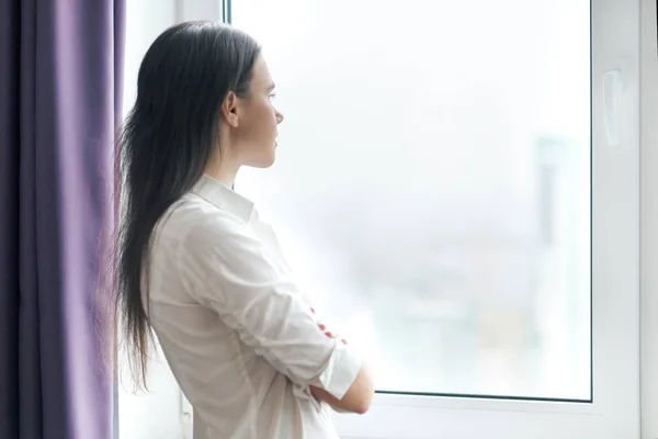 Портрет молодої впевненої бізнес-леді в білій сорочці з схрещеними руками, жінка дивиться у вікно, офіс у хмарочосі хмарний день, копіювати простір — стокове фото